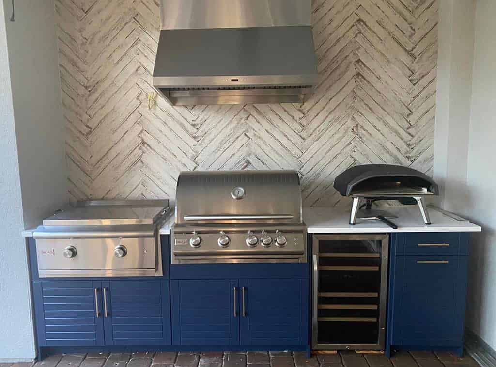 Custom built-in outdoor kitchen with grill and prep space adjacent to a Lowcountry pool